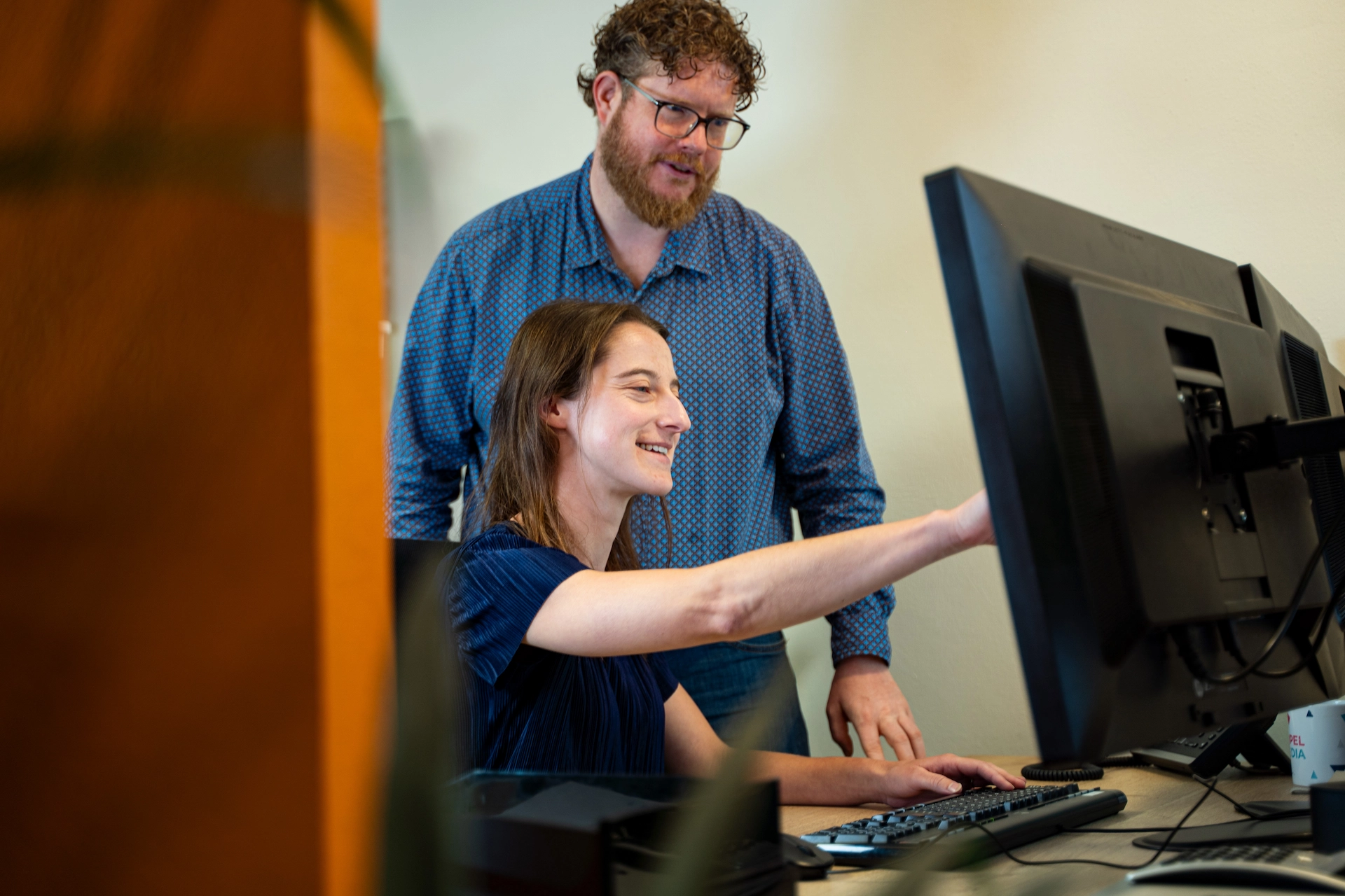 Twee ITAKOM-collega's werken samen achter een monitor